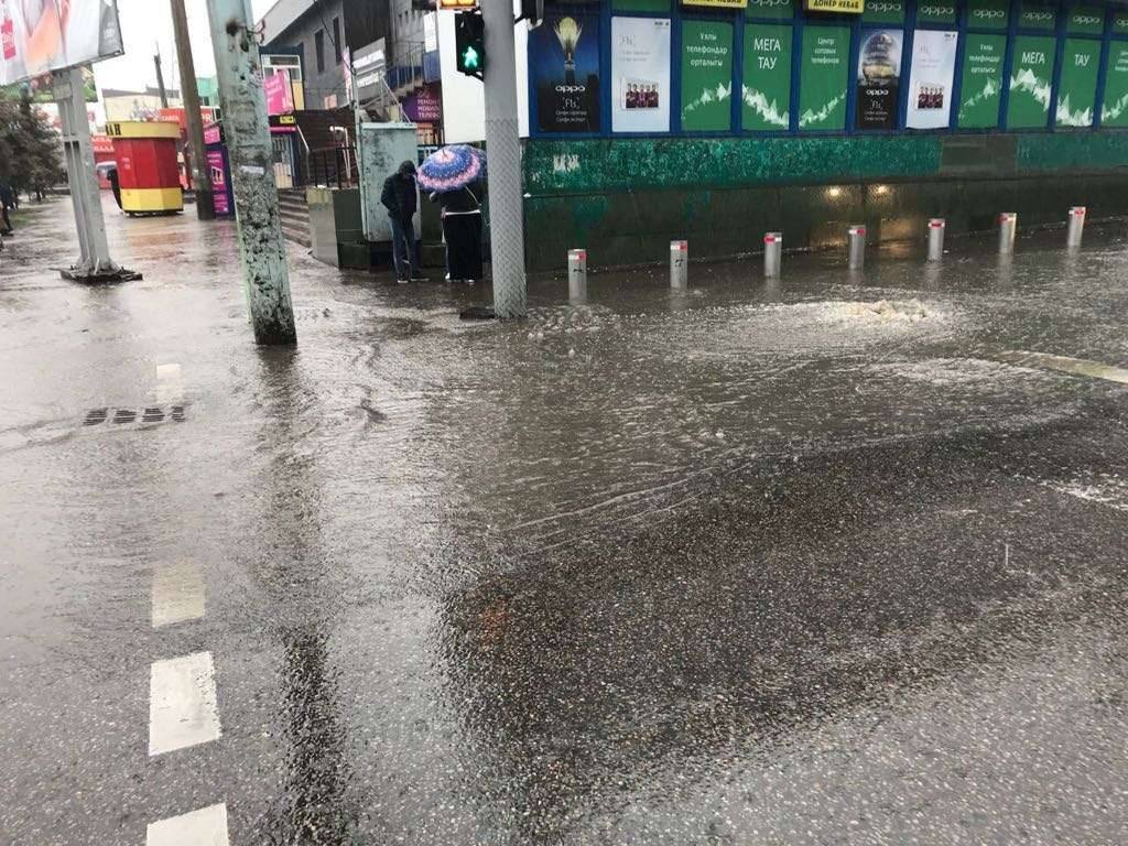 Вода большим потоком бежит по асфальту, не уходя в колодцы