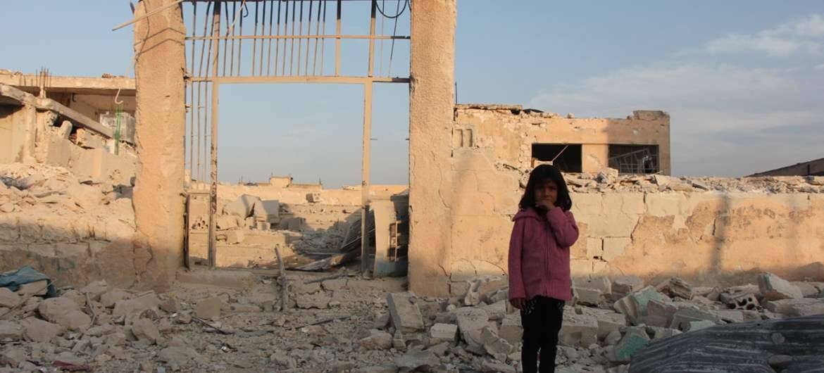 Семилетняя жительница Идлиба перед развалинами, в которые превратилась её школа