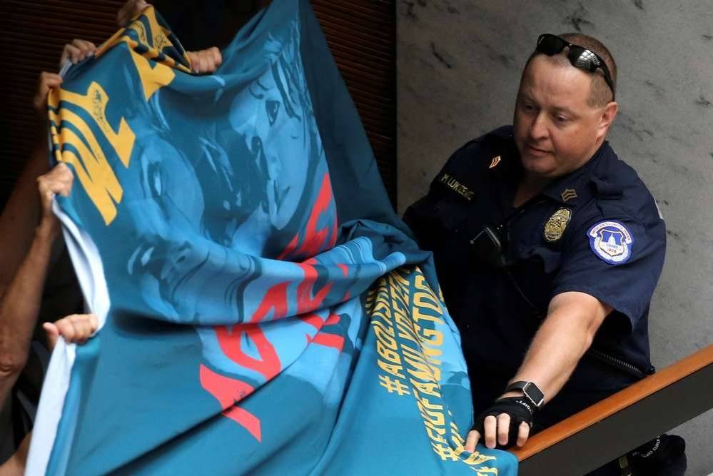 Полицейский отбирает баннер у митингующих